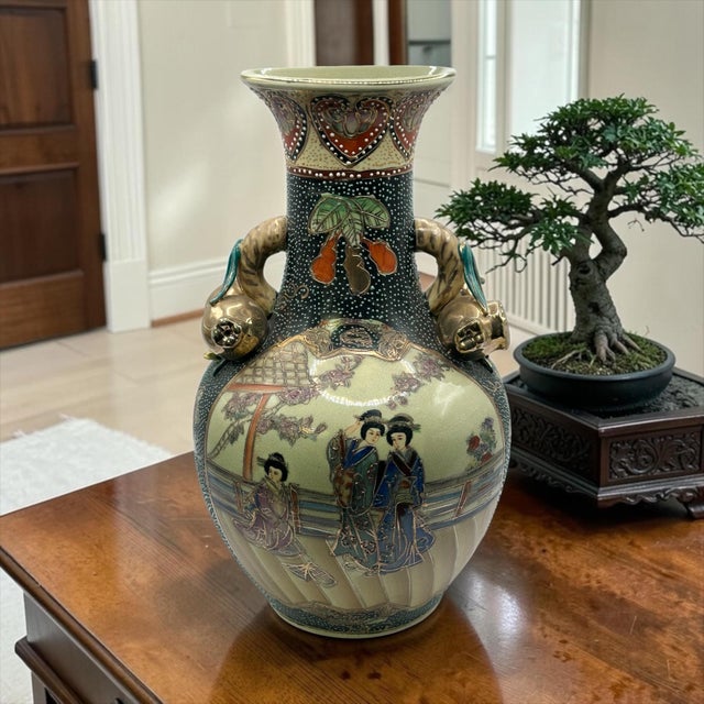 This is a vintage Royal Satsuma style Japanese earthenware vase featuring geisha girls with gilded handles. This porcelain...