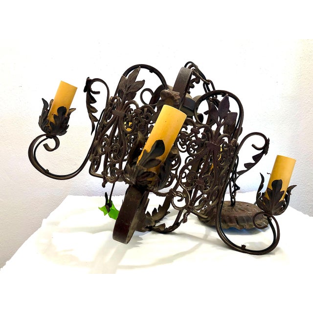 Dating from the 1940s, this Spanish Revival-style wrought iron chandelier features ornate scrollwork, decorative foliage,...