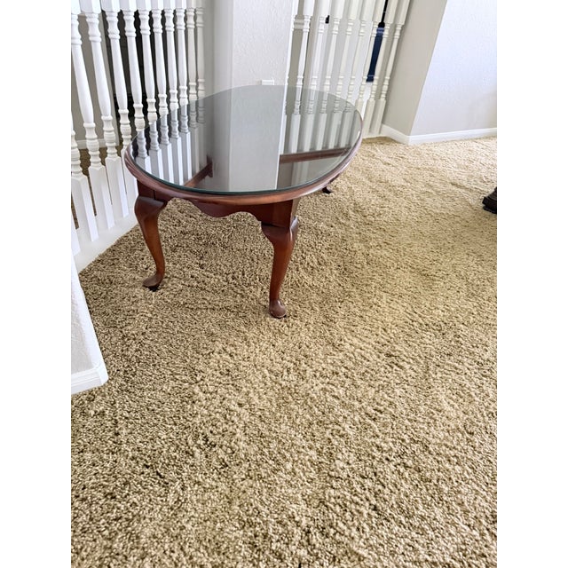 Elegant dark wood coffee table with a tempered glass top and graceful cabriole legs. The glass top showcases the beautiful...