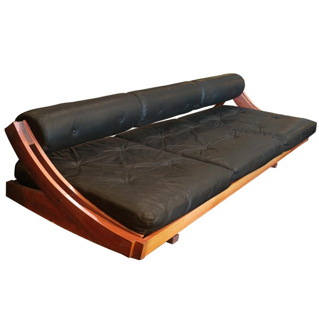 This Italian mid-century sofa is by Gianni Songia for Sormani. The sofa showcases a sculptural sliding frame in Rosewood...