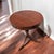A circular vintage side table by Mersman with a warm wood finish, compact drawer, and a graceful pedestal base on three...