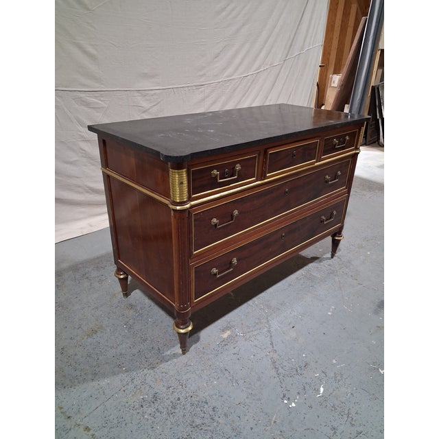 An elegant French Empire period commode crafted in richly figured mahogany and crowned with its original black marble top....