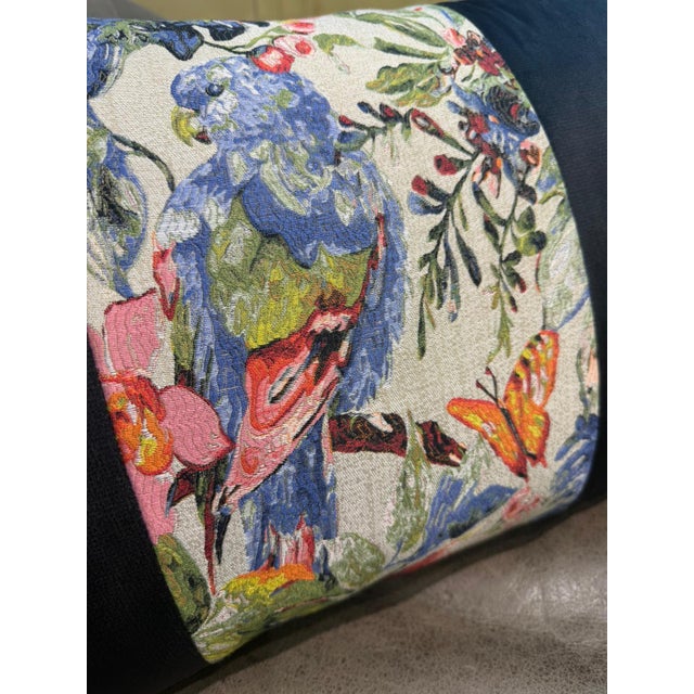 A lumbar cushion cover built around a woven jacquard center strip set against a warm cream ground, showing a large blue...
