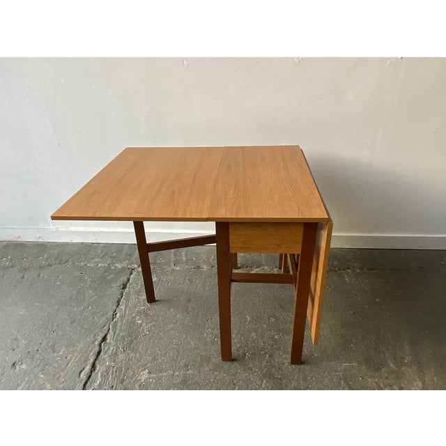 A wide and substantial extending dining table with the original wood grain laminate table top and 2 drop leaves. Supported...
