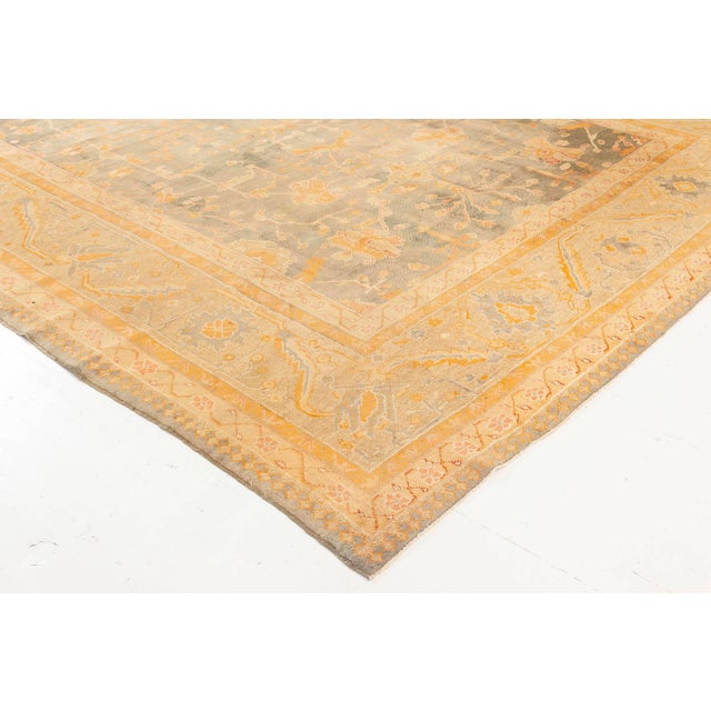 This exquisite antique Oushak rug, woven in Turkey circa 1930, is a masterful representation of Anatolias enduring...