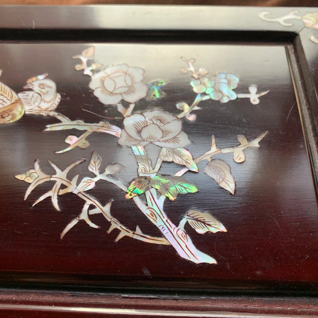 Shiny wood jewelry box with gold colored hardware and design in Mother of Pearl and Abalone shell. Design features...