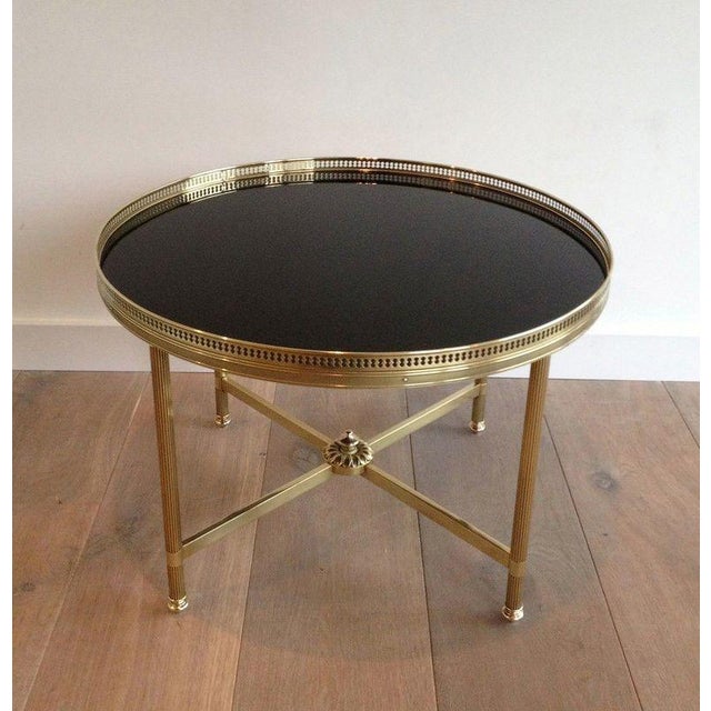 This beautiful round coffee table is made of brass with a black lacquered glass top. French work Attributed to Maison...