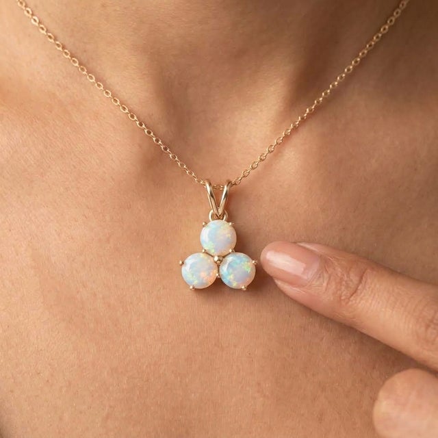 An enchanting three-stone design featuring round-cut natural opals arranged in a graceful trefoil formation, secured in a...
