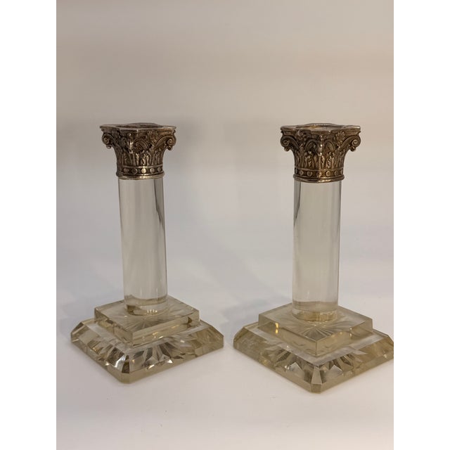 An elegant pair of Neoclassical Revival candlesticks featuring silver-plated Corinthian capitals above substantial clear...