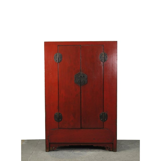 This Chinese antique cabinet shows striking muted aged rich red and stands 66.3 inches tall. The traditional brassware...