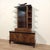 Refined double-body walnut cabinet with a glass display case at the top. While still bearing Art Deco references, it...