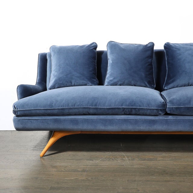 This Mid-Century Modernist sofa, upholstered in luxurious smoked sapphire blue velvet and featuring sculptural supports,...