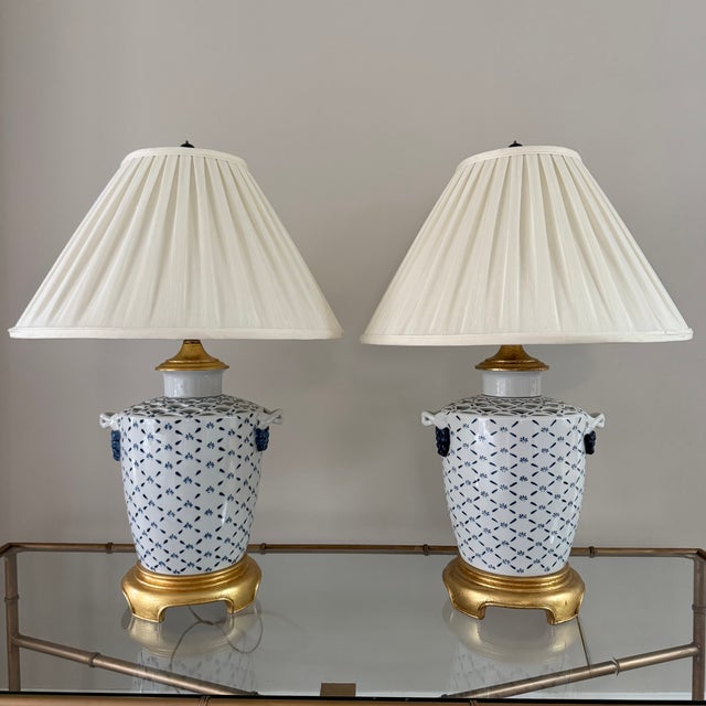 A pair of 1980s Chinoiserie blue and white porcelain urn table lamps featuring a delicate blue criss-cross design with...