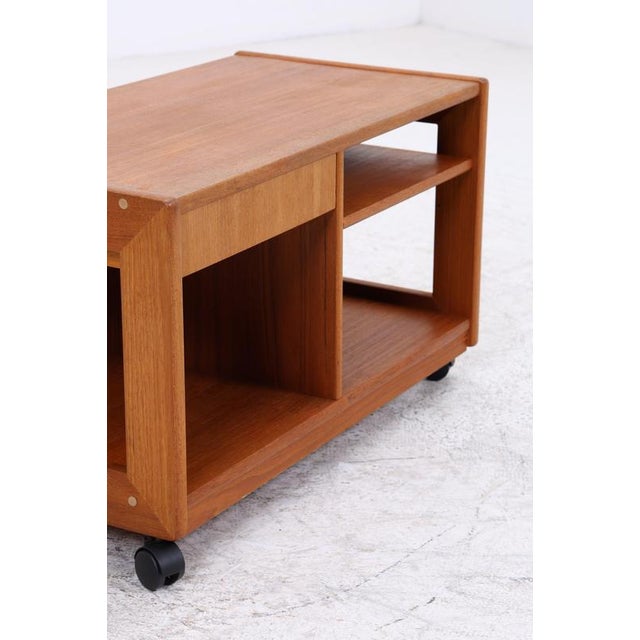 Vintage teak side table with a clean, compact design and four casters. The combination of a drawer and open compartments...