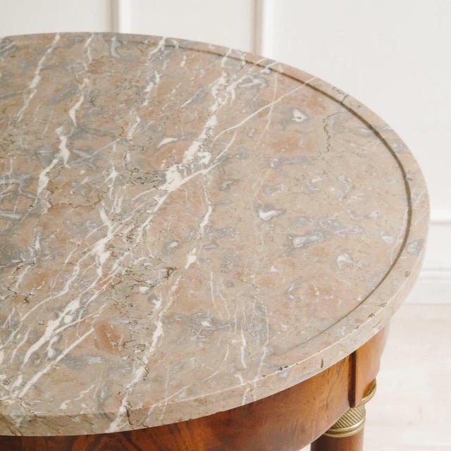Historic round side table from around 1850, stylistically classified as Empire. The combination of a circular marble top,...