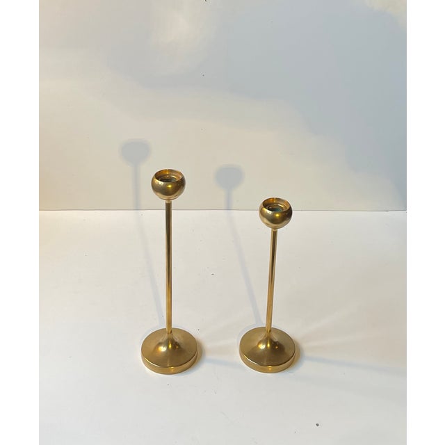 A set of tulip shaped brass candlesticks designed and manufactured in Scandinavia during the 1960s ina style reminiscent...