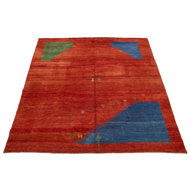 This modern Gabbeh rug is hand-knotted with a contemporary geometric pattern. The red base is accented with green and blue...