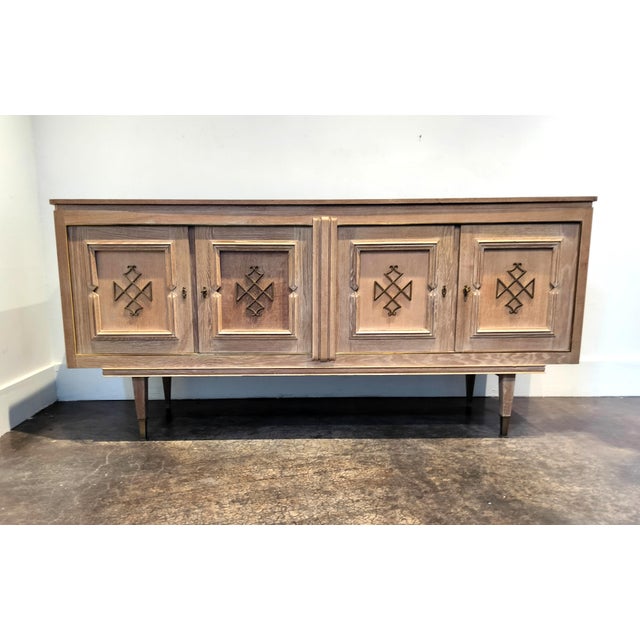 Exceptional, beautifully cerused solid-oak French sideboard/credenza with decorative designs and trim in brass. Finely...