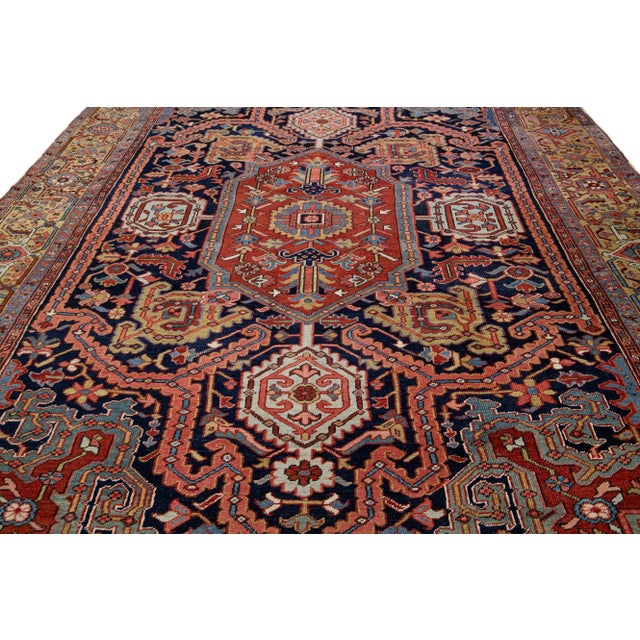 Beautiful Antique Heriz hand-knotted wool rug with a navy-blue and rust field. This Heriz rug has a tan frame and multi-...