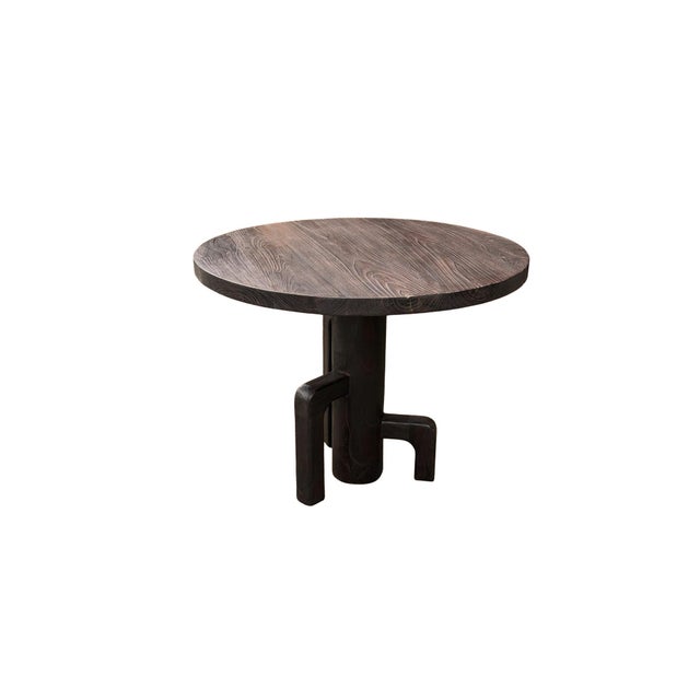 This striking teak wood dining table is a bold expression of craftsmanship and materiality. Finished in a deep dark brown...