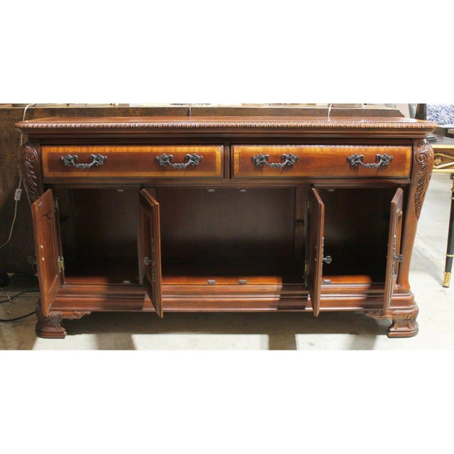 Crafted in a traditional style, this mahogany piece features lighter wood trim outlining the top, drawer fronts, and door...