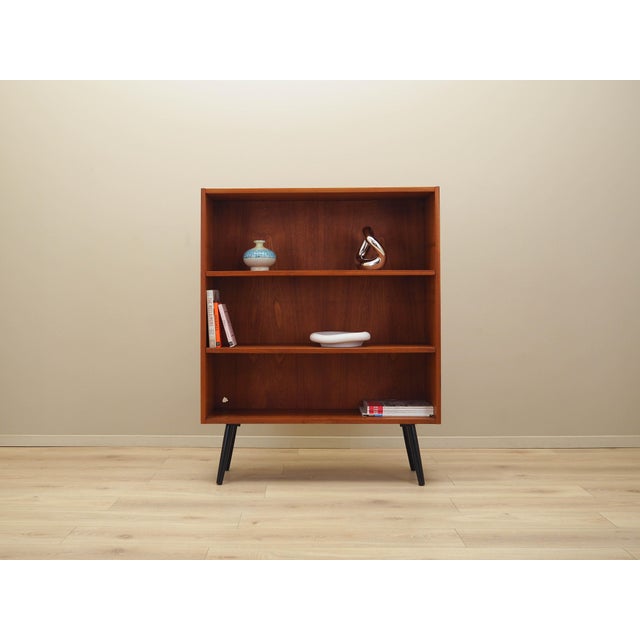 The bookcase was made in the 1970s in Denmark. The structure is covered with teak veneer. The legs are made of solid wood...