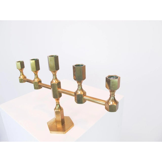 This candleholder in brass was manufactured by Gusum Metall Slöjd. Imprinted by Maker