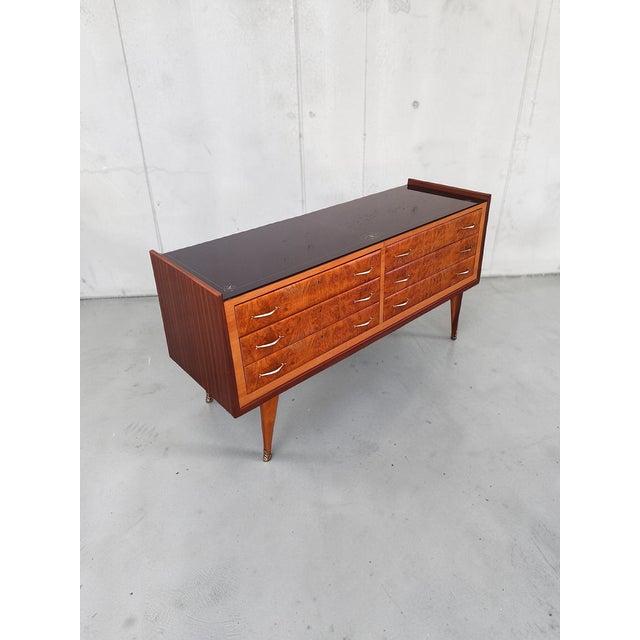 A large chest of drawers made in Italy in the 1950s with quality materials: wood, decorated glass for the top, and brass...