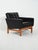 Swedish armchair by AB Futura from the 1960s/70s in black faux leather with teak legs, square volumes, and enveloping...