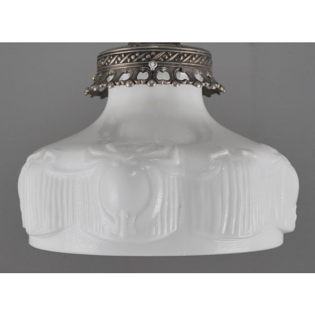 Victorian style pendant light with an ornate white glass shade paired with a nickel finish steel chain fitter. This...