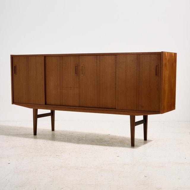 Danish teak highboard with unique handles from the 1960s. The highboard has four sliding doors and a mirror, two small...
