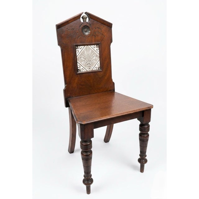 This antique hall chair features a distinctive pediment-style back and a triangular seat, characteristic of late Victorian...
