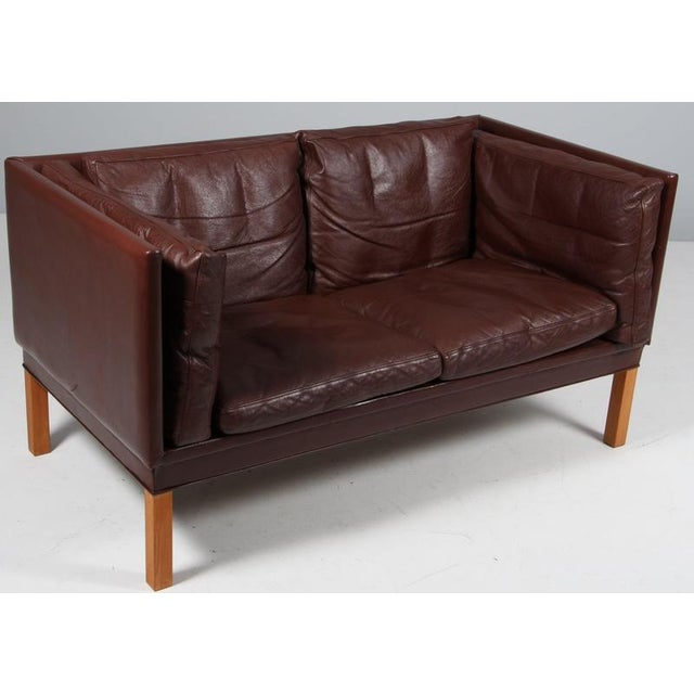 Illum Wikkelsø 1919-1999. Two-seat sofa, freestanding, upholstered in brown leather, loose cushions with down filling, oak...