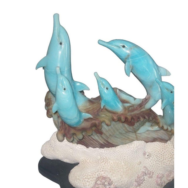 A vibrant and finely carved blue quartzite sculpture depicting a lively group of dolphins emerging playfully from stylized...
