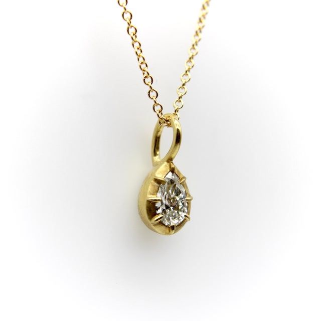 This beautiful pear-shaped diamond is elegantly set in an 18k yellow gold collet setting—one of the oldest gemstone...