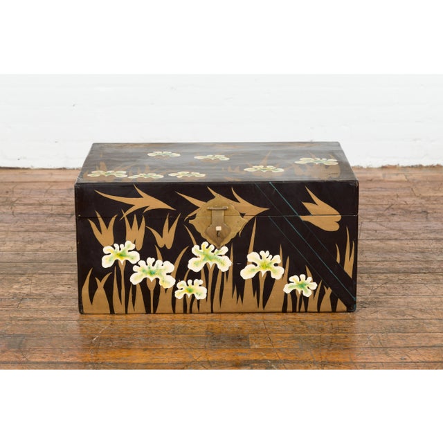 An antique Japanese late Meiji period black lacquer blanket chest from the early 20th century, with gold, white and green...