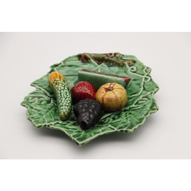 A Portuguese trompe l’oeil vine leaf from the 1900s, featuring a cucumber, strawberry, watermelon, grapes, and an apple....