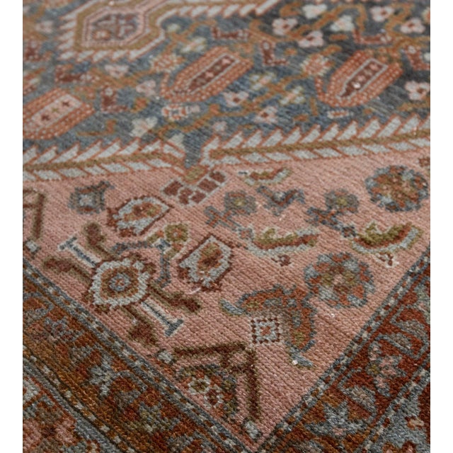 This Malayer rug has a shaded indigo field with a bold flowerhead and boteh vine around a central dusty-pink serrated...