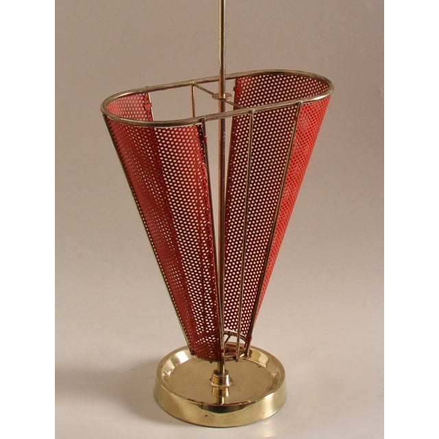 A very unusual umbrella stand in the shape of a half-open umbrella. The design with the red perforated metal is...