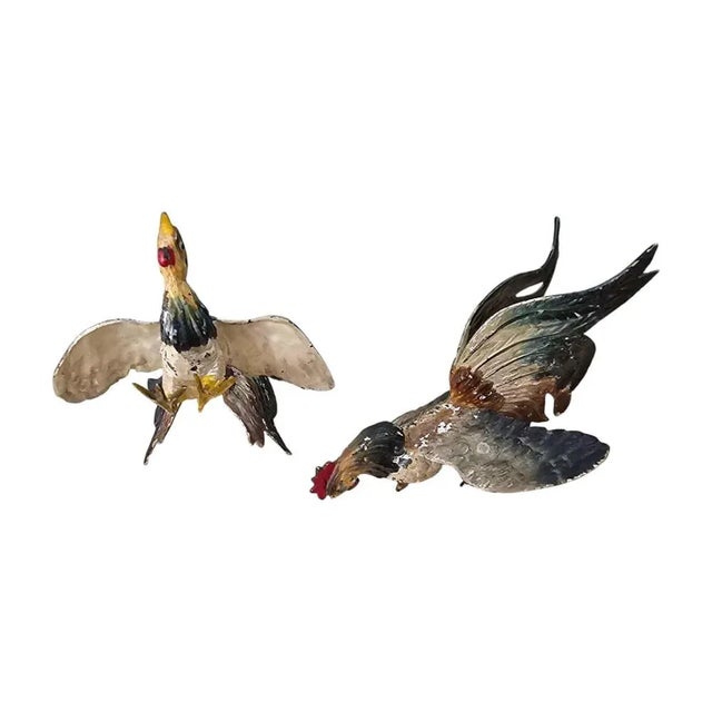 Add a touch of vintage charm to your decor with this delightful pair of painted metal rooster figurines from the early...