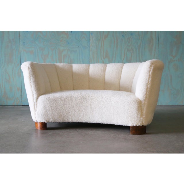 A 1940s Danish channel tufted banana sofa. Chunky curved mahogany legs mimics the shape of the sofa supporting a curvy...