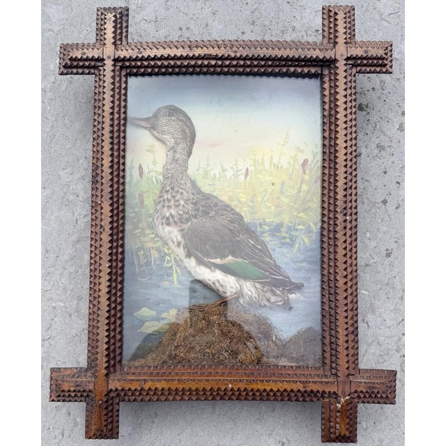 Behind a typical Tramp Art frame is a box. On the back of the box is a gouache painting of a half duck in profile style....