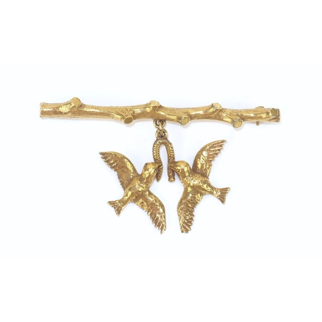 Beautiful gold plated brooch depicting a tree branch suspending a pair of love birds. Though the design appears to be from...