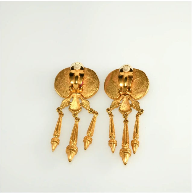 Egyptian revival dangle earrings crafted of gold-plated metal with matte finish decorated with enameling and cabochon...