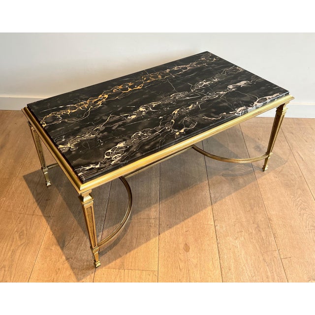 This coffee table is made of bronze with a black Portor marble top. It is a French work in the style of Maison Jansen....