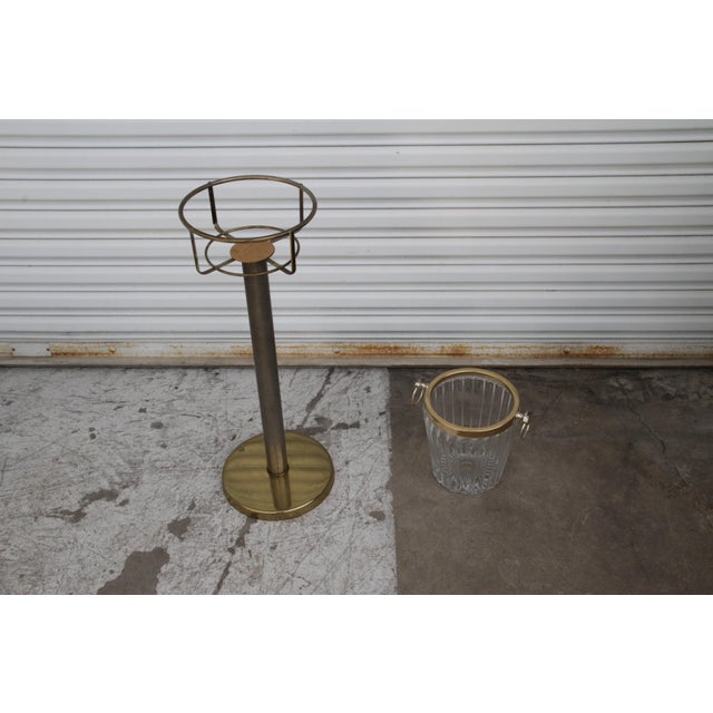 Vintage 1970s champagne glass ice bucket with brass stand. The ice bucket has a brass rim and handles. The stand has a...