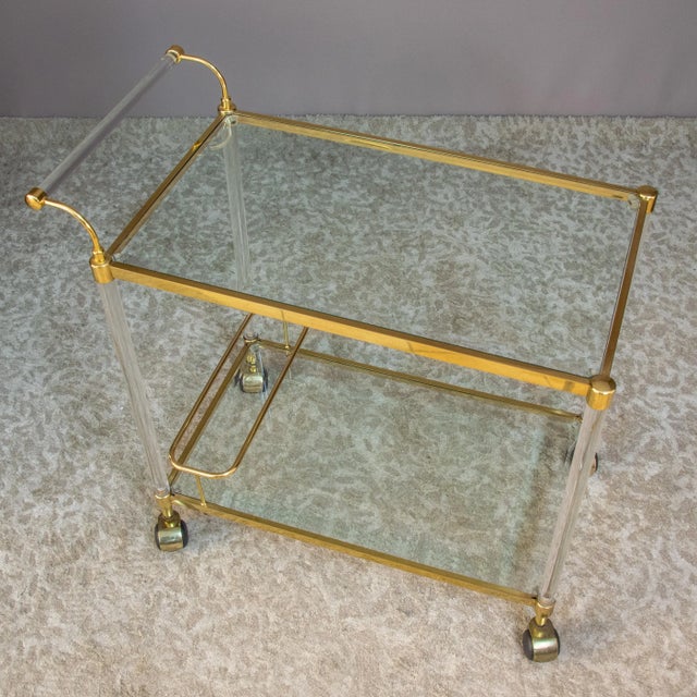 Elegant and functional food trolley Brass and acrylic glass Two crystal shelves The lower shelf features a double bottle...