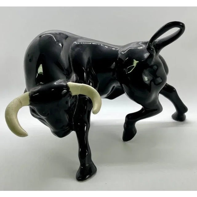 An exquisite pair of Mid-Century Modern figurines of two black bulls with white horns made of ceramics. One bull is...