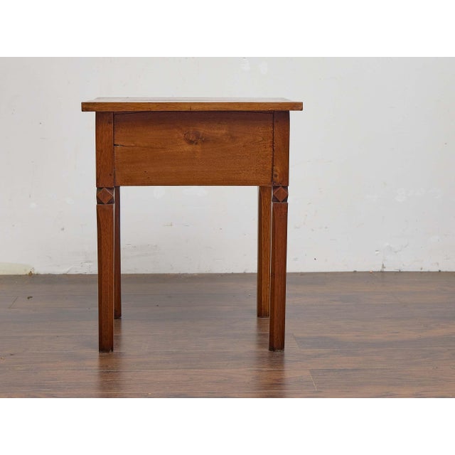A French walnut side table from the 19th century, combining simple lines with refined carved details. The square top rests...