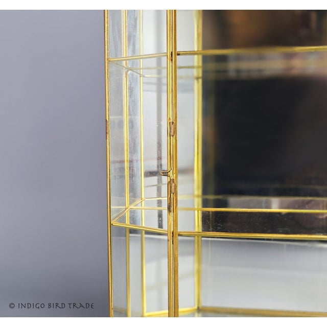 Large Vintage Glass and Brass Curio Display Cabinet This tabletop display cabinet features a brass frame, a mirrored back,...